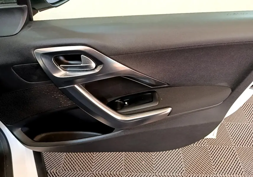 Vue rapprochée de la porte avant gauche noire du Peugeot 2008 avec poignée et commandes de vitre argentées.