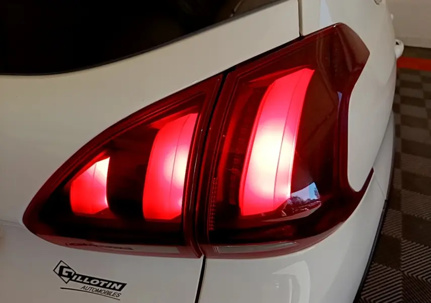 Gros plan sur le feu arrière droit rouge d’une Peugeot 2008 blanche, avec partie de la carrosserie visible.