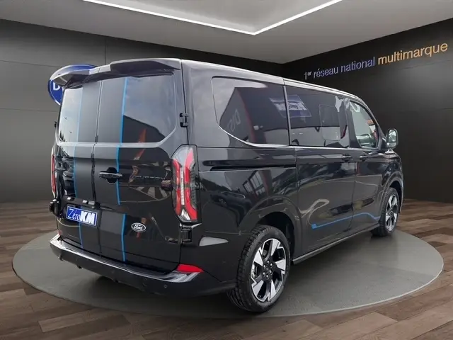 Vue 3/4 arrière droite du Ford Transit Fourgon noir 2026 avec vitres teintées et jantes alliage distinctives.
