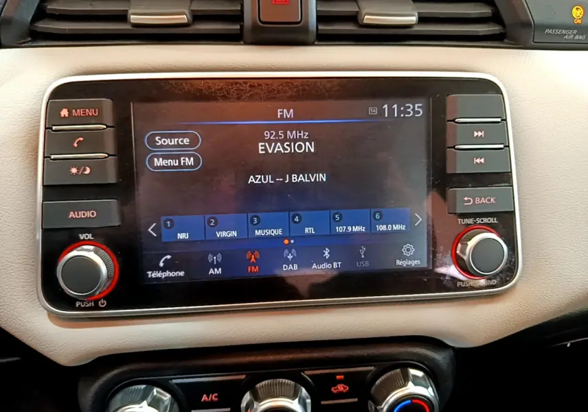 Écran tactile central de la Nissan Micra blanche 2022 affichant la radio FM et commandes audio intégrées.