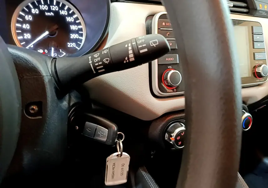 Vue rapprochée du tableau de bord et volant d'une Nissan Micra blanche 2022, avec clé insérée et commandes visibles.