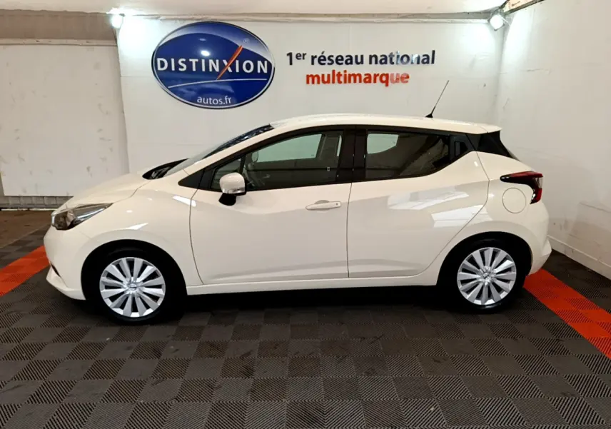 Profil côté gauche d'une Nissan Micra blanche 2022 IG-T 92 Acenta dans un showroom avec sol noir et orange.