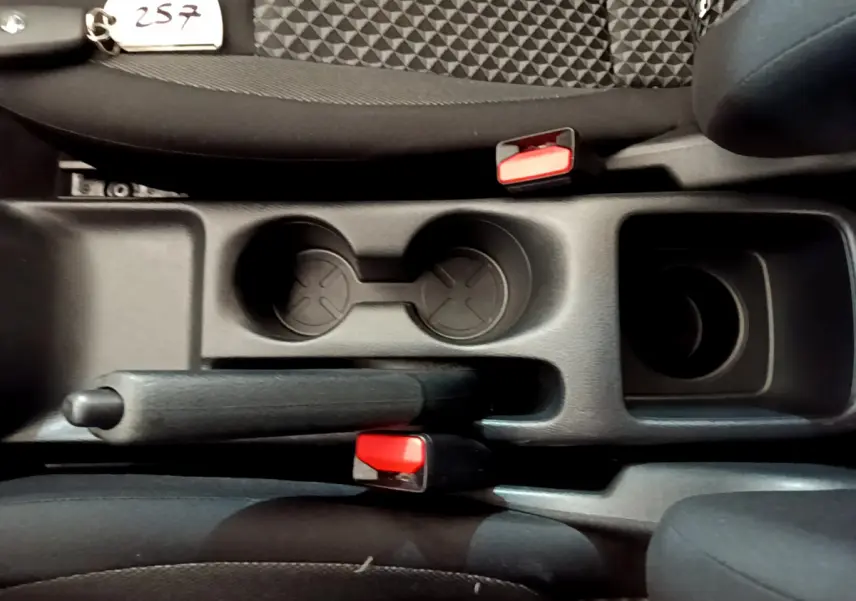 Vue plongeante sur la console centrale noire de la Nissan Micra Acenta 2022, avec frein à main et porte-gobelets.