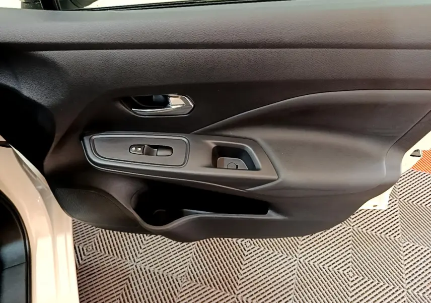 Vue rapprochée de la porte avant gauche noire d'une Nissan Micra blanche 2022, avec commandes de vitres électriques.