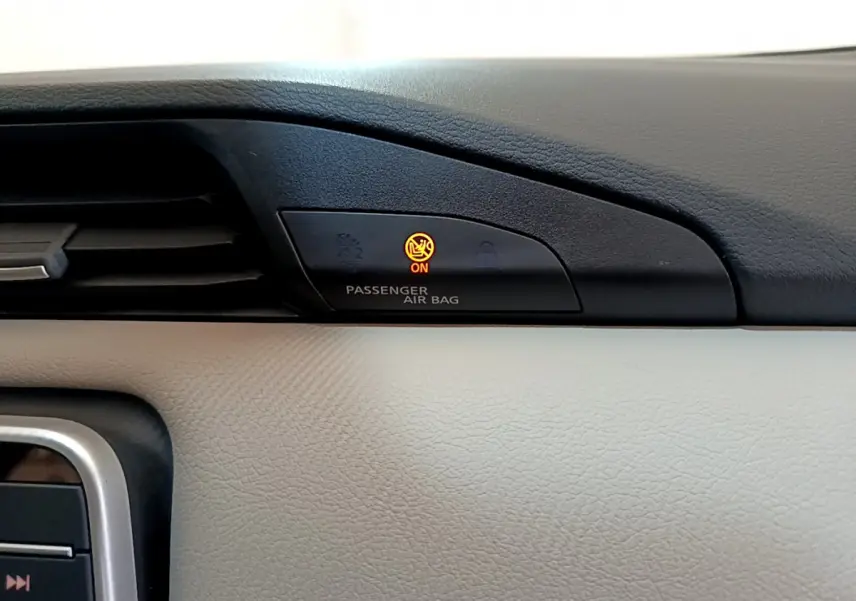 Gros plan sur le tableau de bord beige et noir du Nissan Micra blanc 2022, voyant airbag passager allumé en orange