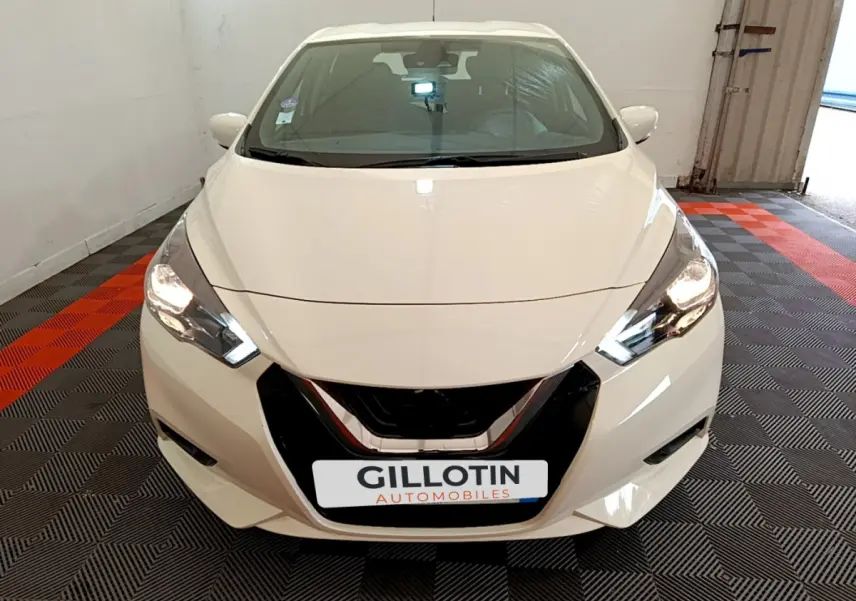 Vue frontale d'une Nissan Micra IG-T 92 Acenta blanche avec phares LED allumés dans un garage.