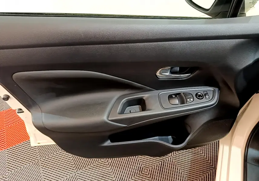 Vue rapprochée de la porte avant gauche blanche d'une Nissan Micra 2022 avec commandes électriques et poignée chromée.