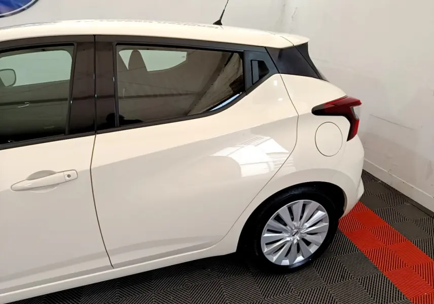 Vue côté gauche arrière d'une Nissan Micra IG-T 92 Acenta blanche avec jantes alliage et vitres teintées.