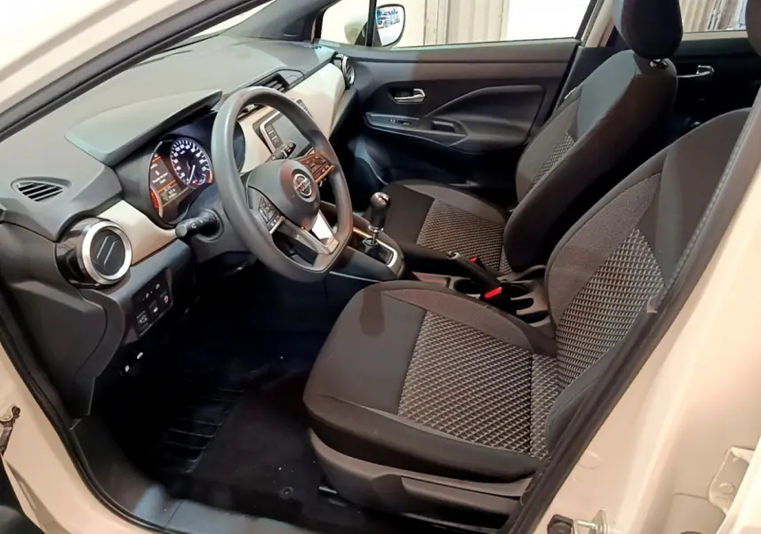 Intérieur avant de la Nissan Micra blanc 2022, vue côté conducteur montrant sièges noirs et tableau de bord moderne.