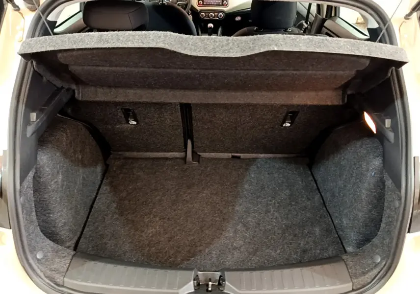 Coffre ouvert vu de l'arrière d'une Nissan Micra blanche 2022, intérieur gris avec tablette de séparation relevée.