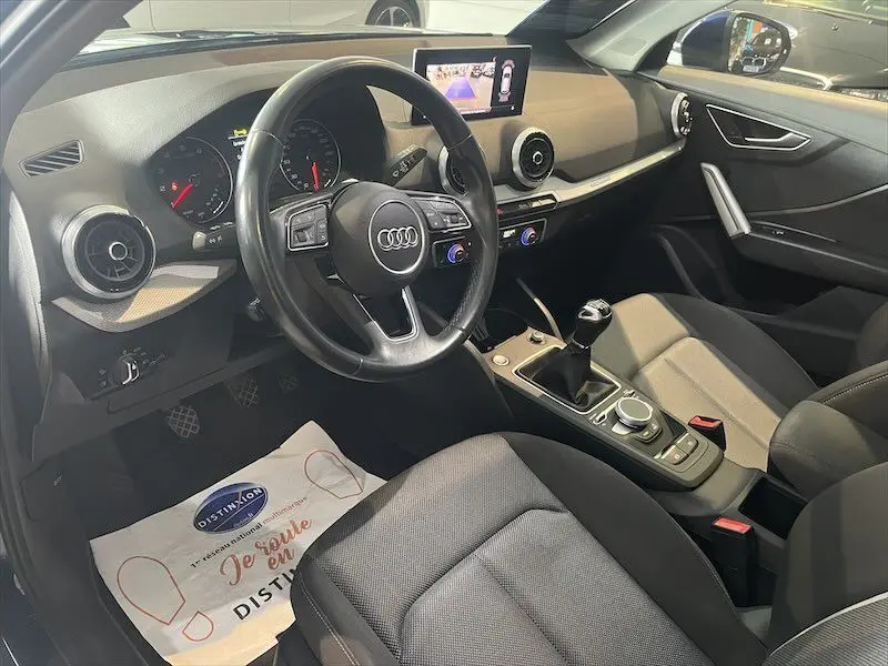 Vue intérieure côté conducteur de l'Audi Q2 30 TFSI S-Line 2021, avec volant multifonction et levier de vitesse manuel.