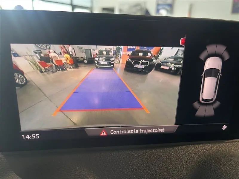 Vue caméra de recul d'un Audi Q2 bleu Navarre métal en stationnement intérieur avec repères de trajectoire visibles.