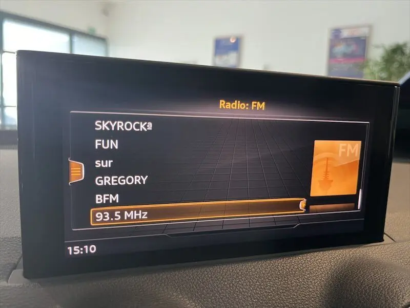 Écran multimédia intérieur de l'Audi Q2 30 TFSI S-Line 2021 affichant les stations FM, dans un habitacle lumineux.