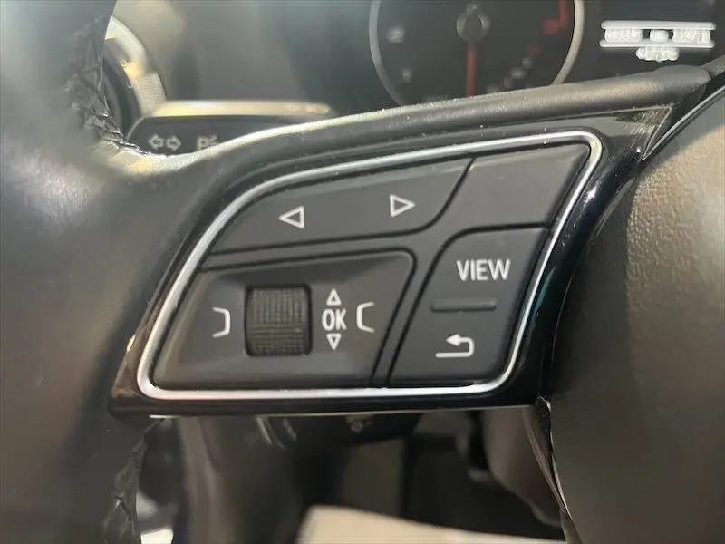 Gros plan sur les commandes au volant côté gauche de l'Audi Q2 30 TFSI S-Line 2021, intérieur noir.