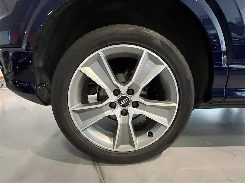 Gros plan sur la roue avant droite d'un Audi Q2 bleu Navarre Métal avec jante alliage S-Line à cinq branches.