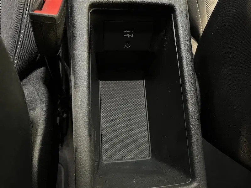 Vue rapprochée de la console centrale noire de l'Audi Q2 30 TFSI S-Line 2021, avec ports USB et AUX visibles.