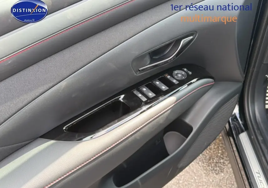 Détail de la porte avant gauche du Hyundai Tucson noir 2026 avec commandes de vitres et poignée intérieure chrome.