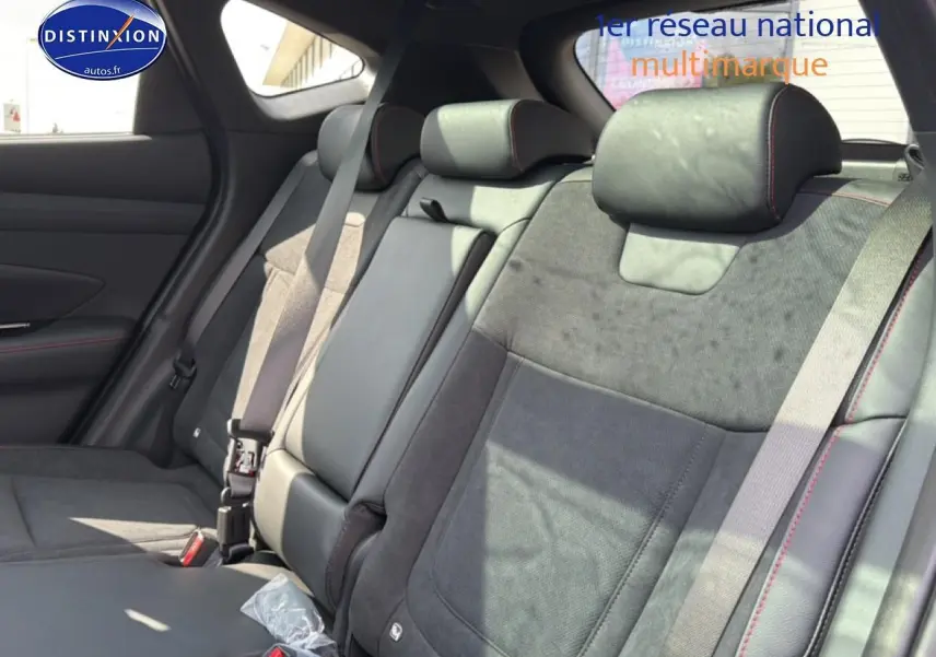 Vue latérale intérieure montrant les sièges arrière en cuir noir et alcantara avec surpiqûres rouges du Hyundai Tucson 2026.