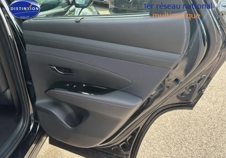 Vue rapprochée de la porte arrière gauche noire du Hyundai Tucson 2026 avec garniture cuir et surpiqûres rouges.