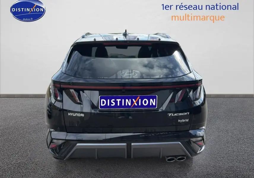 Vue arrière d'un Hyundai Tucson noir hybride avec feux arrière LED et double sortie d'échappement visible.