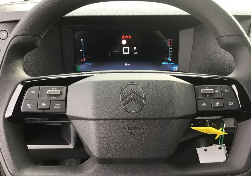 Vue rapprochée du volant noir du Citroën Jumpy gris titane, avec commandes intégrées et tableau de bord numérique.