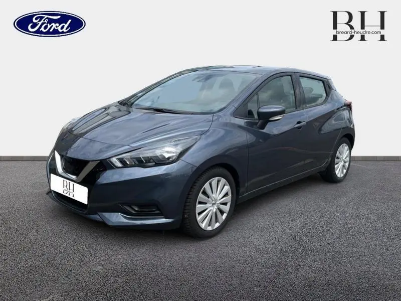 Nissan Micra gris acier vue 3/4 avant droit, mettant en valeur ses phares anguleux et jantes alliage.