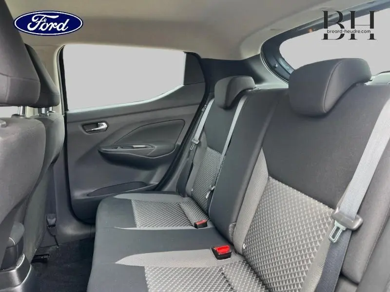 Vue intérieure arrière côté gauche de la Nissan Micra 2022, sièges tissu bi-ton noir et gris avec ceintures visibles.