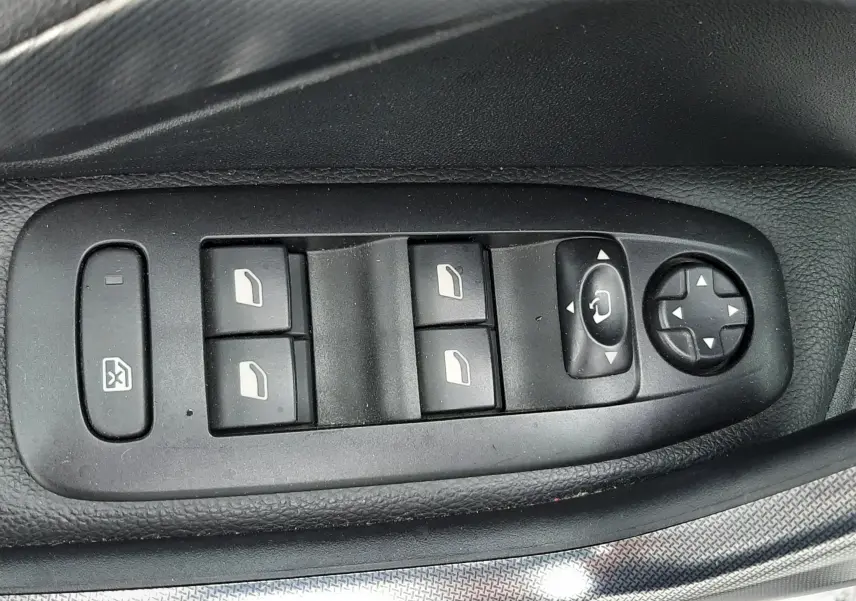 Gros plan sur les commandes des vitres et des rétroviseurs côté conducteur d'une Peugeot 2008 blanche de 2017.