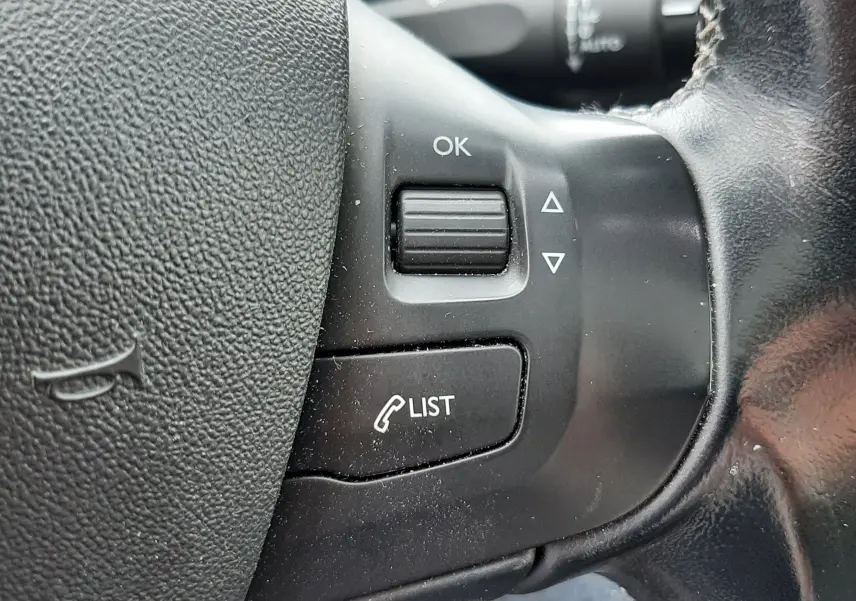Gros plan sur les commandes au volant en cuir noir d'une Peugeot 2008 blanche de 2017, version diesel 1.6 BlueHDi.