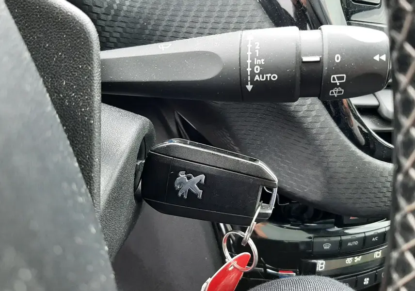 Gros plan sur la clé Peugeot insérée dans le contact d'un 2008 2017, avec commandes de l'essuie-glace visibles.