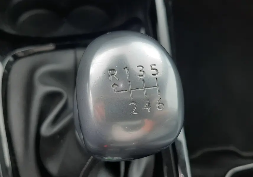 Gros plan sur le levier de vitesses manuel gris argenté du Peugeot 2008 blanc de 2017, montrant les six rapports et la marche arrière.