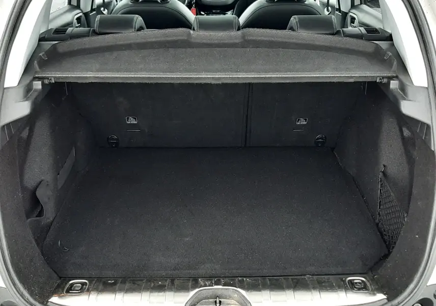 Coffre ouvert vu de l'arrière d'un Peugeot 2008 blanc, intérieur noir avec tablette cache-bagages en place.