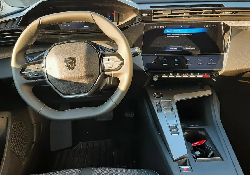 Vue intérieure du poste de conduite de la Peugeot 308 2025, volant compact et écran tactile central moderne.