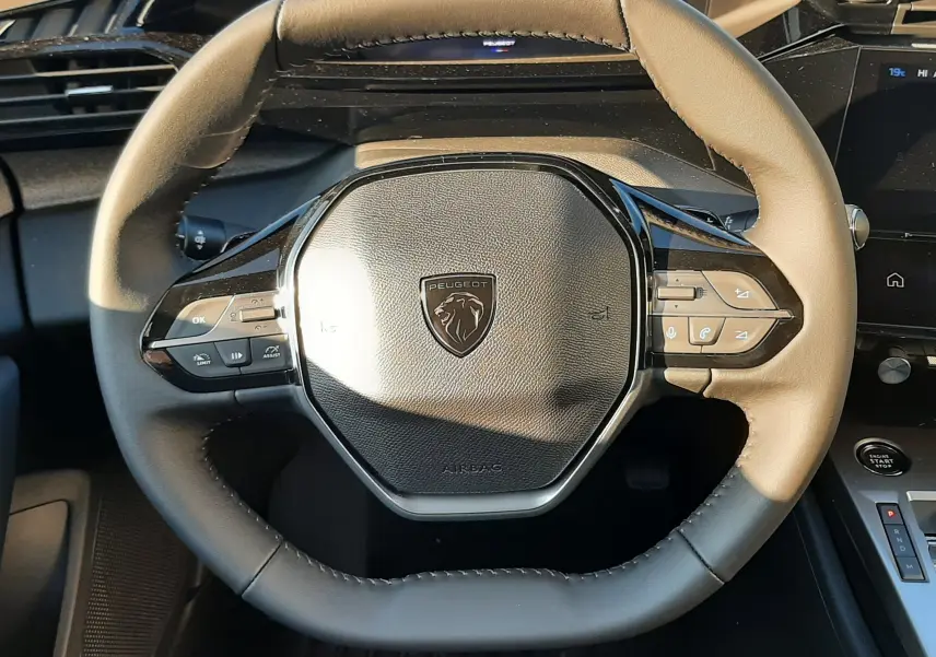 Volant cuir bicolore beige et noir de la Peugeot 308 2025 BlueHDi, avec commandes intégrées et tableau de bord digital.