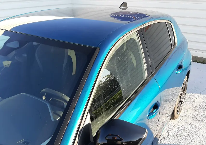 Vue 3/4 avant droit d'une Peugeot 308 Bleu Obsession avec rétroviseur noir brillant et toit foncé.