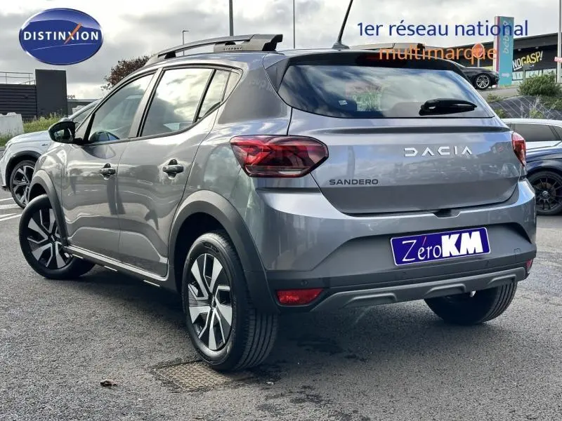 Vue 3/4 arrière droite d'une Dacia Sandero gris métallisé avec toit noir et jantes alliage modernes.