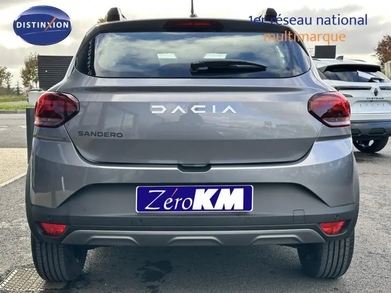 Vue arrière d'une Dacia Sandero gris métallisé avec logo et feux arrière distinctifs visibles.