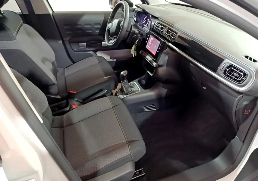 Vue intérieure côté conducteur de la Citroën C3 blanche 2023 avec tableau de bord noir et écran tactile central.
