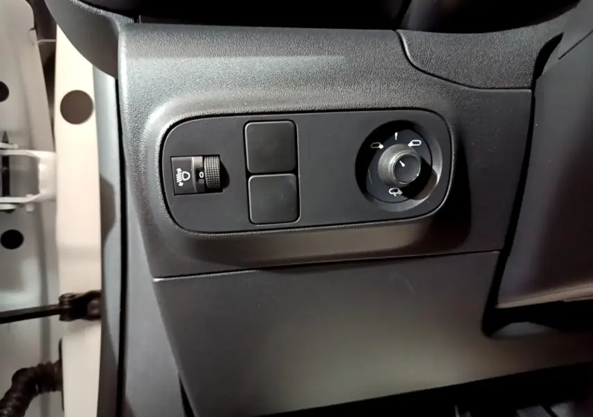 Vue rapprochée des commandes de réglage des phares et des rétroviseurs côté conducteur d'une Citroën C3 blanche 2023.