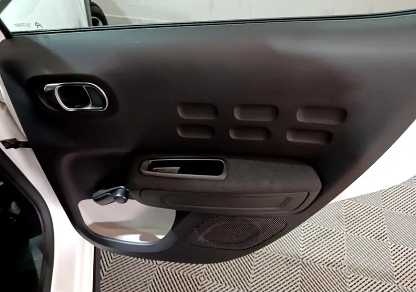 Intérieur de la porte côté gauche blanche de la Citroën C3 2023 avec poignée noire et haut-parleur intégré.