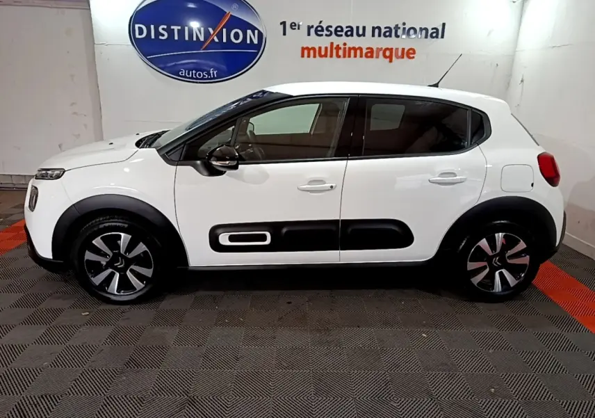 Profil côté gauche d'une Citroën C3 blanche 2023 avec protections latérales noires et jantes stylisées.