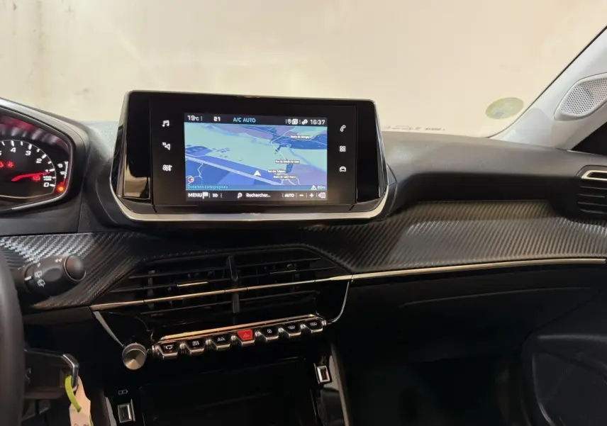 Vue intérieure du tableau de bord de la Peugeot 2008 orange, avec écran tactile de navigation et finition carbone.
