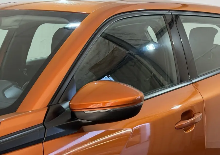 Gros plan sur le rétroviseur droit orange et la porte avant droite d’un Peugeot 2008 2022 en intérieur.