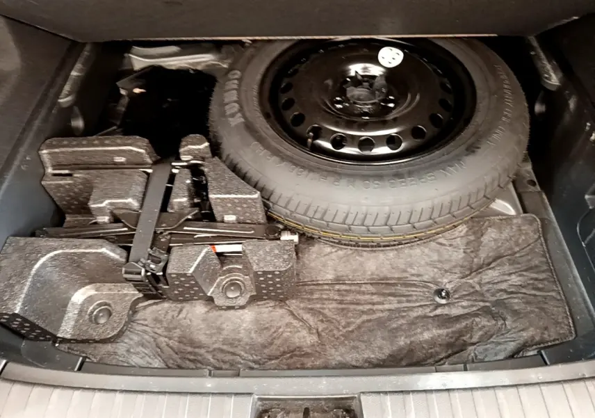 Coffre ouvert du Renault Arkana gris clair 2023 montrant la roue de secours et le kit de réparation sous le plancher.