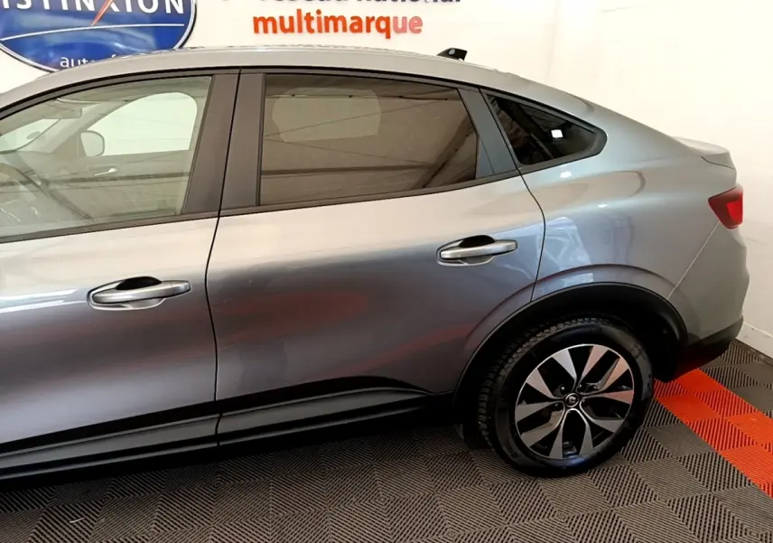 Vue latérale droite d'un Renault Arkana gris clair 2023 avec jantes alliage et vitres teintées.