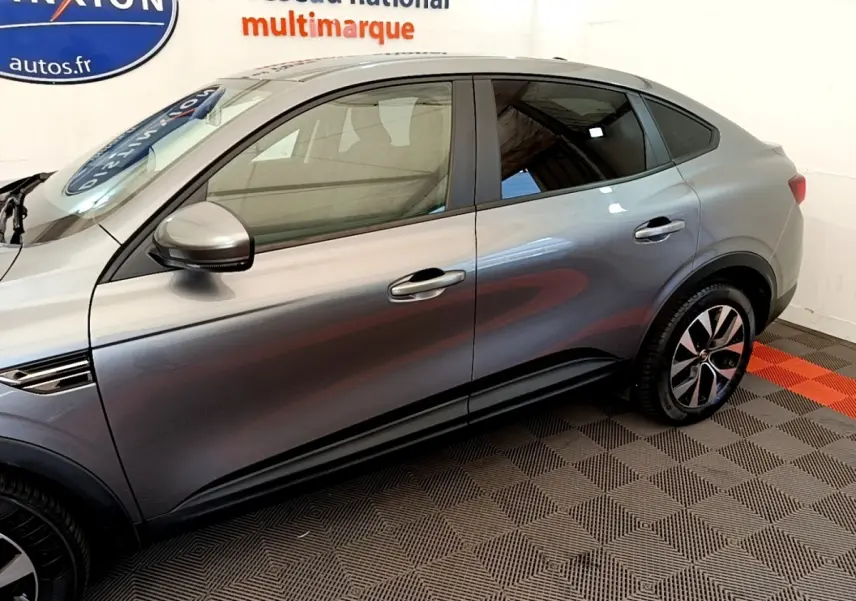 Vue latérale droite d'un Renault Arkana gris clair Evolution E-Tech hybride, soulignant ses jantes et lignes fluides.