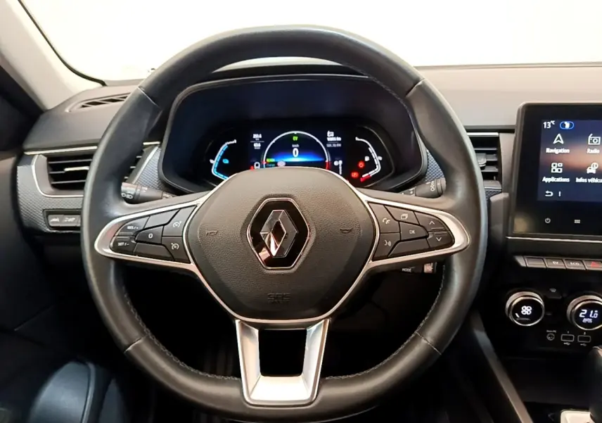 Vue rapprochée du volant en cuir noir du Renault Arkana 2023 avec tableau de bord numérique et écran tactile central.