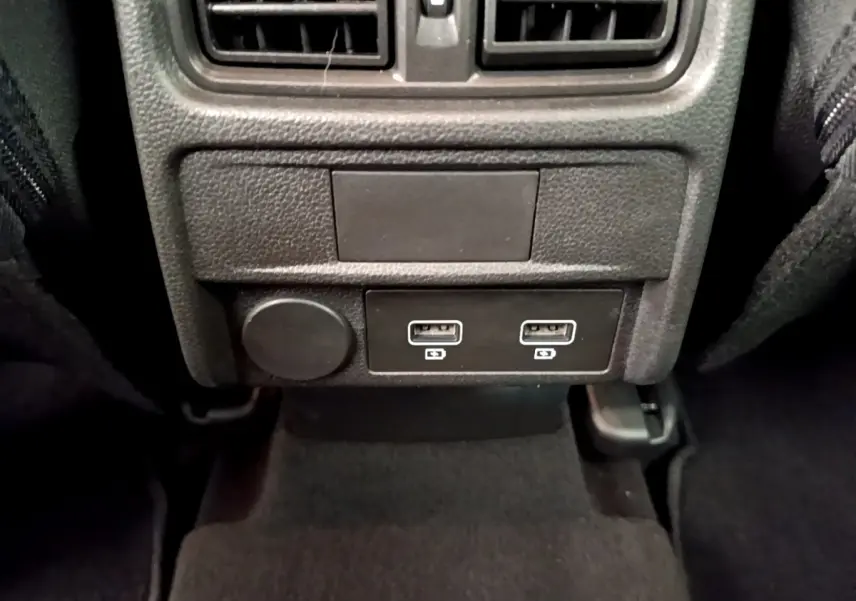 Vue rapprochée des ports USB doubles et prise 12V arrière dans l’habitacle noir du Renault Arkana gris clair.