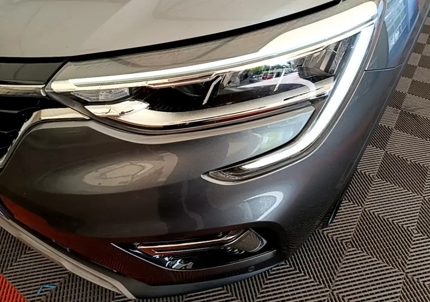 Gros plan sur le phare avant droit gris clair du Renault Arkana Evolution E-Tech 2023 avec détails LED et calandre brillante.