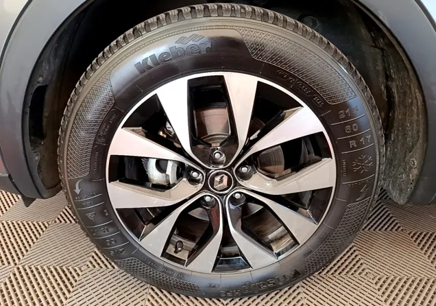 Gros plan sur la roue avant gauche du Renault Arkana gris clair, mettant en valeur la jante alliage bicolore et le pneu Kleber.